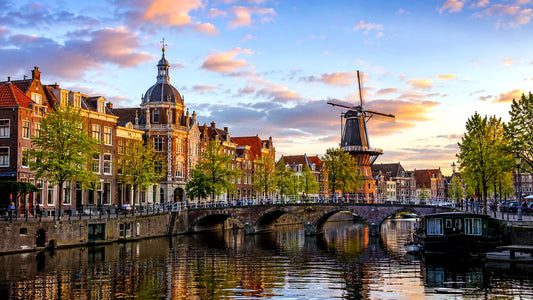 Breedbeeldfoto van de historische grachten, bruggen en molen De Valk in Leiden, Nederland, bij zonsondergang – sfeervolle 8K landmarkfoto voor meubels herstofferen en meubelstoffering in Leiden.