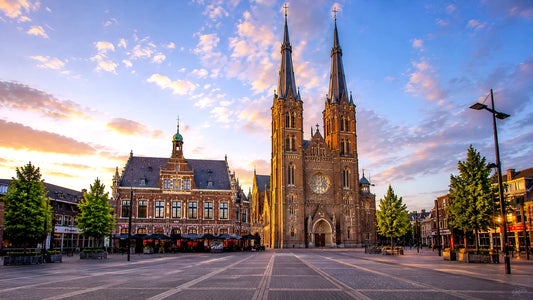 “Breedbeeldfoto van de Heuvelse Kerk en het historische stadsplein in Tilburg, Nederland, bij zonsondergang – hoogwaardige 8K landmarkfoto voor meubels herstofferen en meubelstoffering in Tilburg